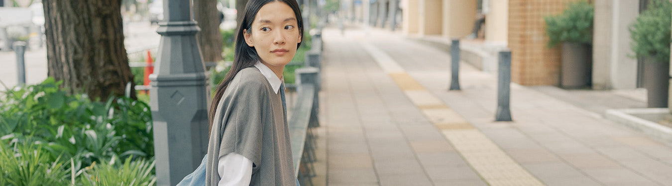 Women's New Arrival - Woman sitting on bench in MUJI shirt & sweater.