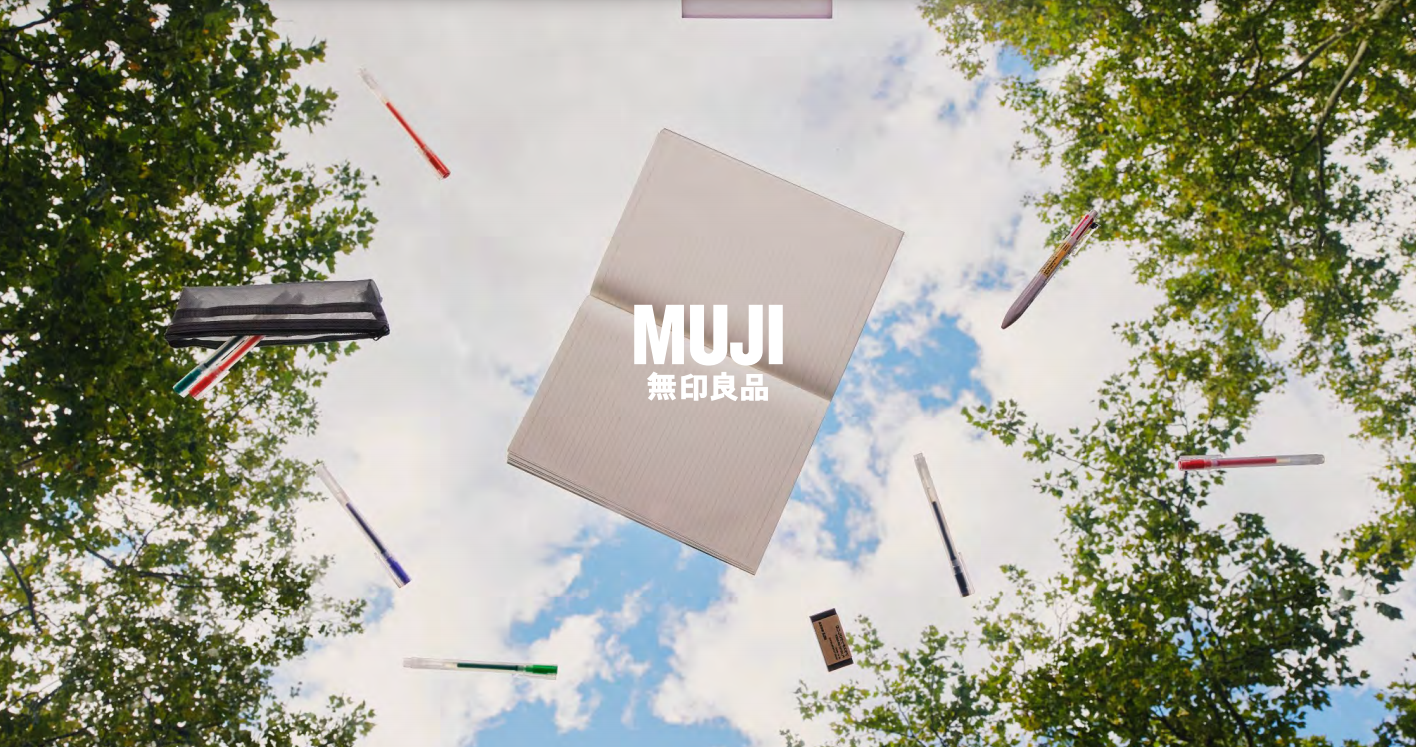 Muji Back to School Supplies.  Open notebook, pens, and other supplies on thrown in the air