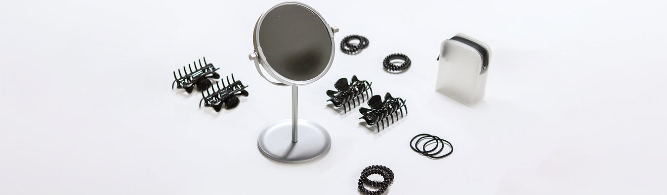 A small vanity mirror, hairclips, and hair ties neatly arranged on a table. 