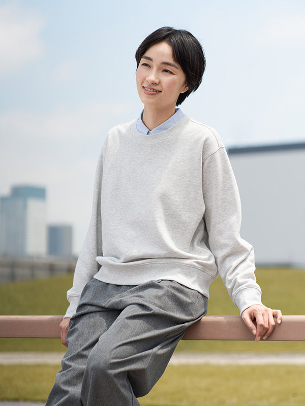 Woman sitting on a railing with a cityscape in the background