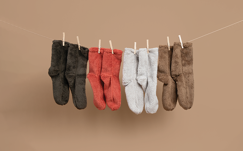 Set of cozy socks hanging on a clothesline against a brown background