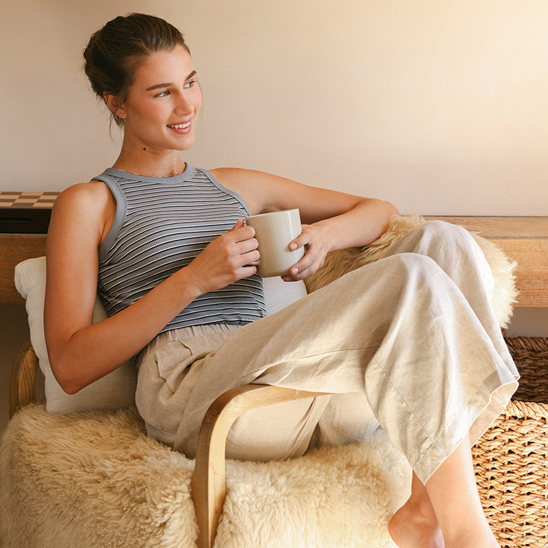 Woman wearing linen dress leaning on a blue wall. 