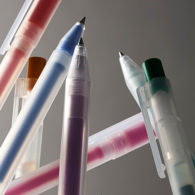 A close-up group of translucent gel pens in assorted colors, including pink, blue, purple, green, and orange, arranged diagonally against a neutral gray background.