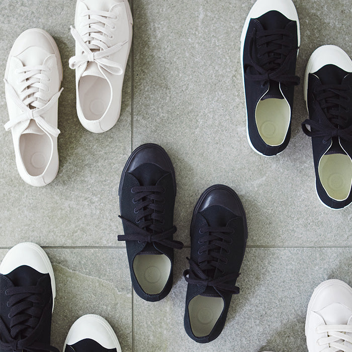 Pair of black and white sneakers on a gray tiled floor