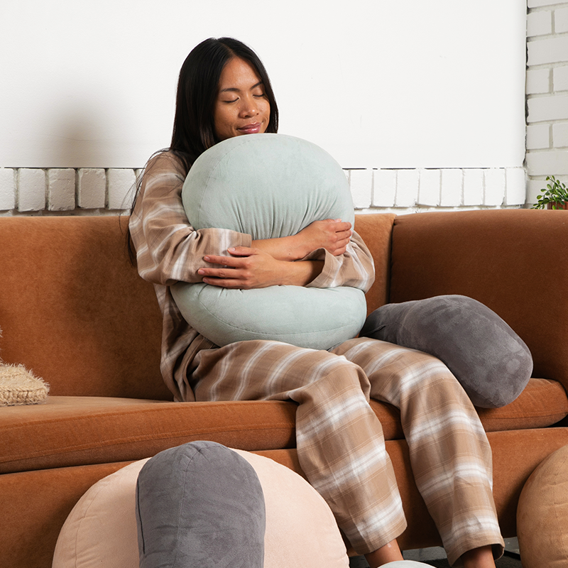 Woman sitting on a couch holding a soft cushion.