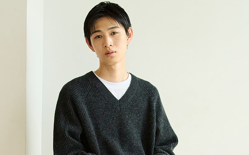 Person wearing a dark gray sweater against a plain background