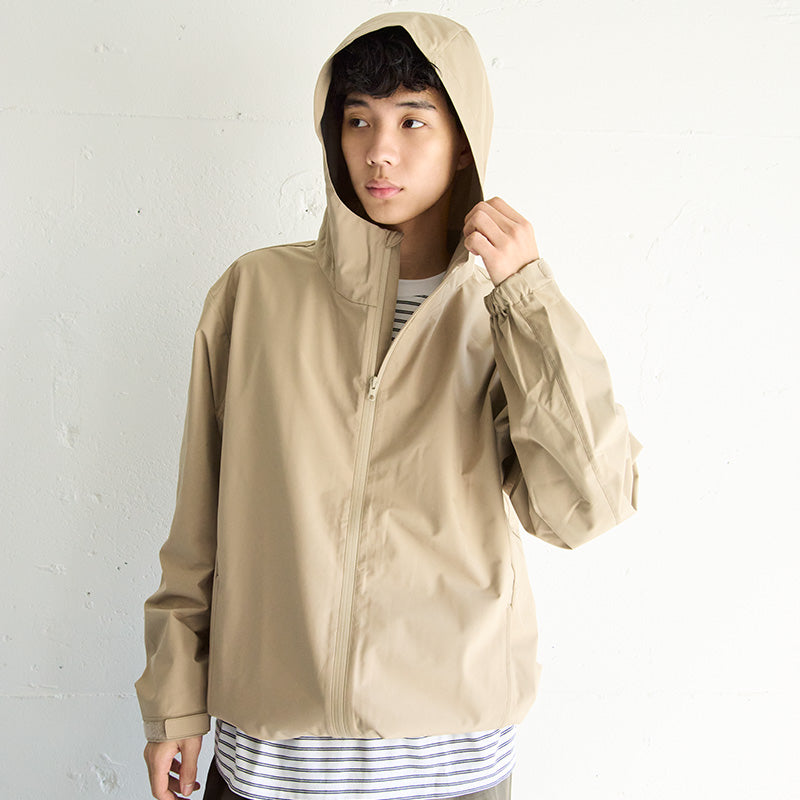 Man wearing a beige water repellent hooded jacket and blue and white striped shirt. 
