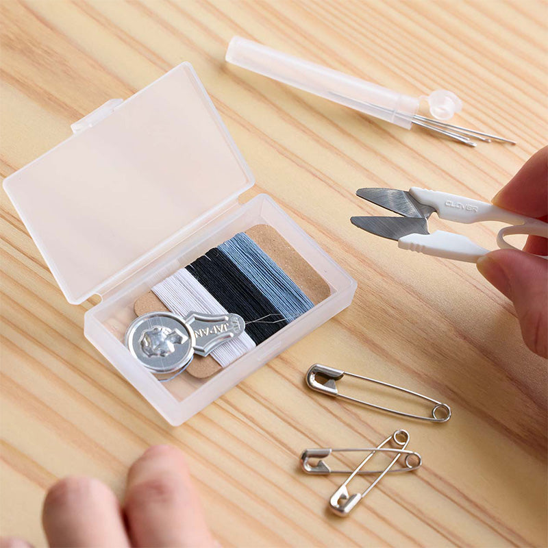Thread kit with scissors, pins, and thread spool on a wooden surface